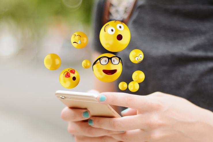 cellulare tra le mani ed emoticon